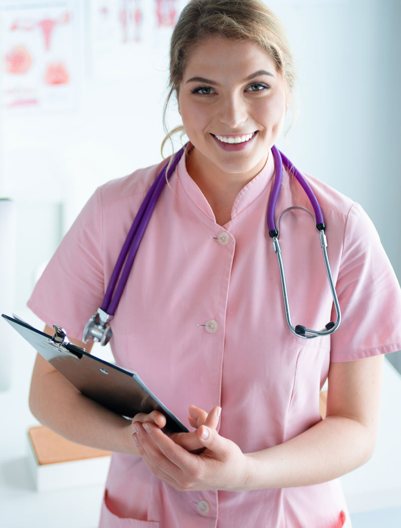 smiling nurse in pink scrub holding clipboard